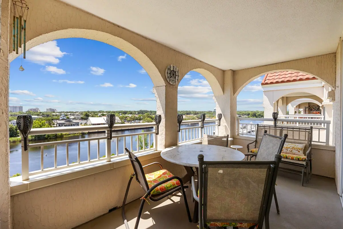 Covered balcony with a dining table and chairs overlooking a waterway