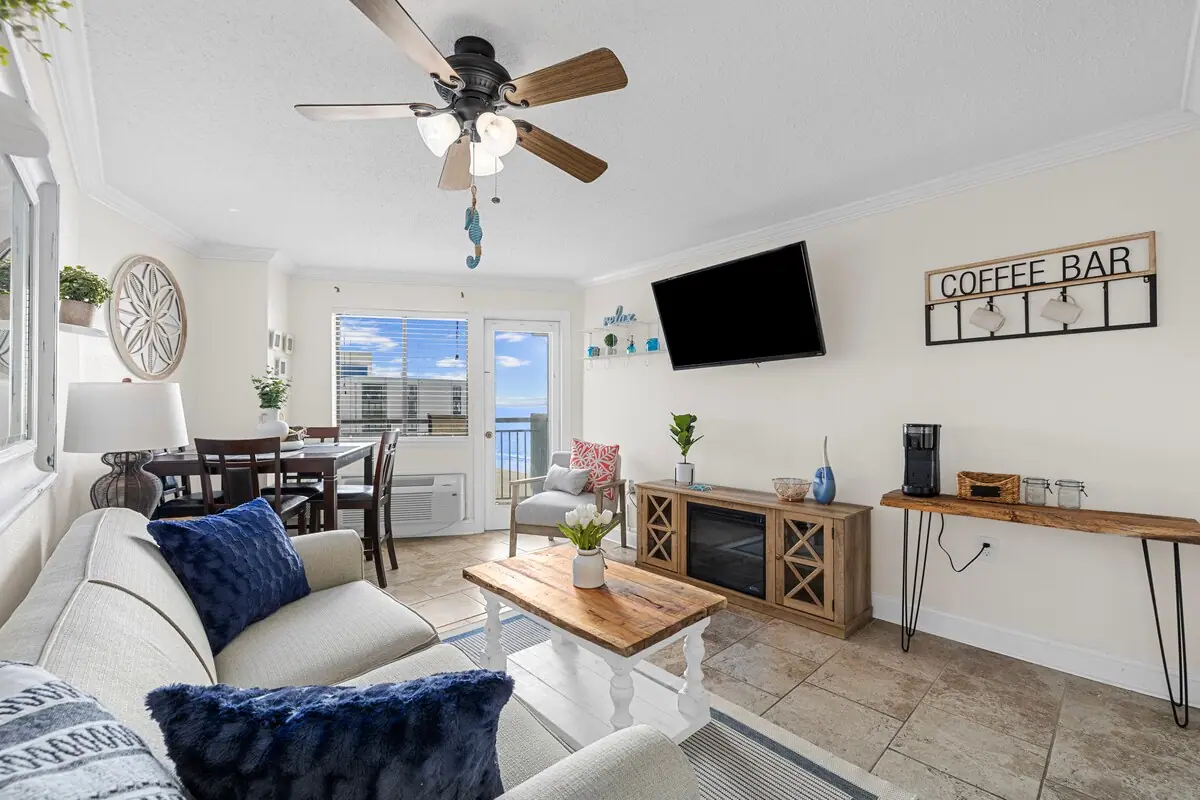 Living and dining area with a sofa, television, and sliding balcony doors