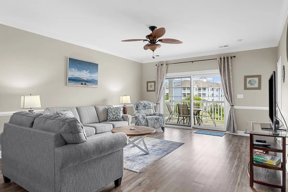 Living room with gray sofas and sliding doors to a balcony