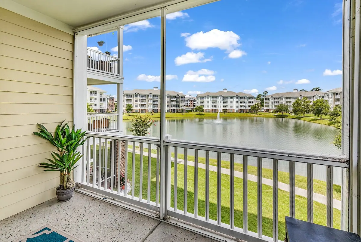 Screened balcony overlooking a lake and neighboring condo buildings