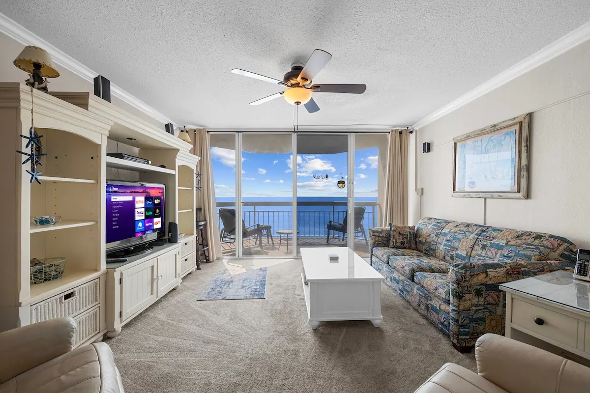 Living room with a patterned sofa and glass doors facing the ocean