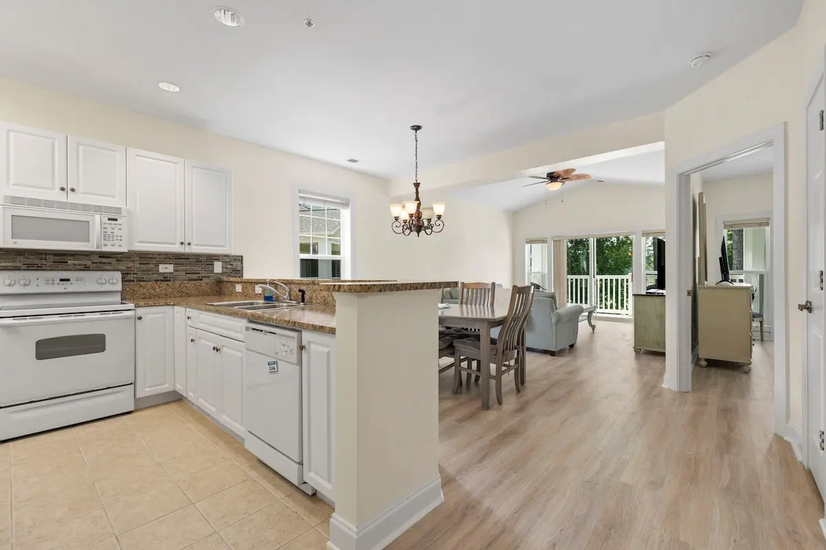 White kitchen opening to a dining area and living room