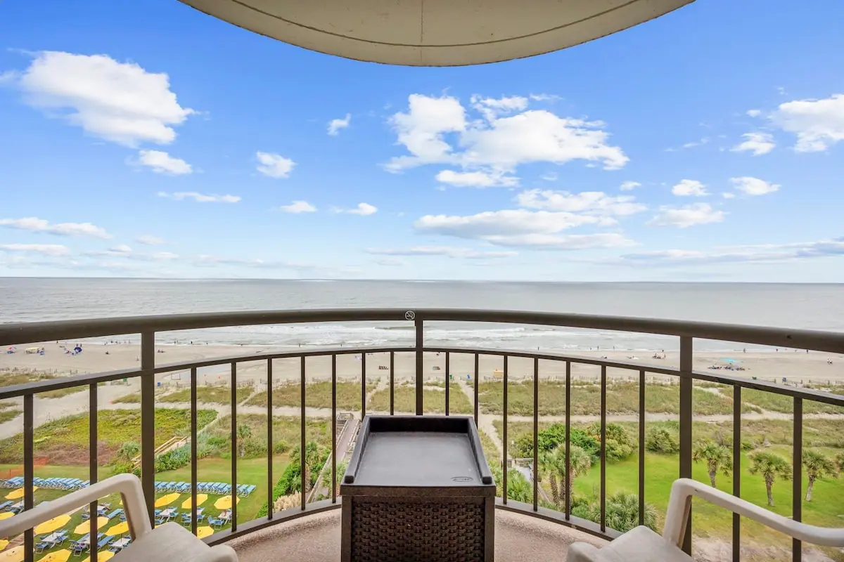Balcony chairs and table facing the sandy beach and open ocean