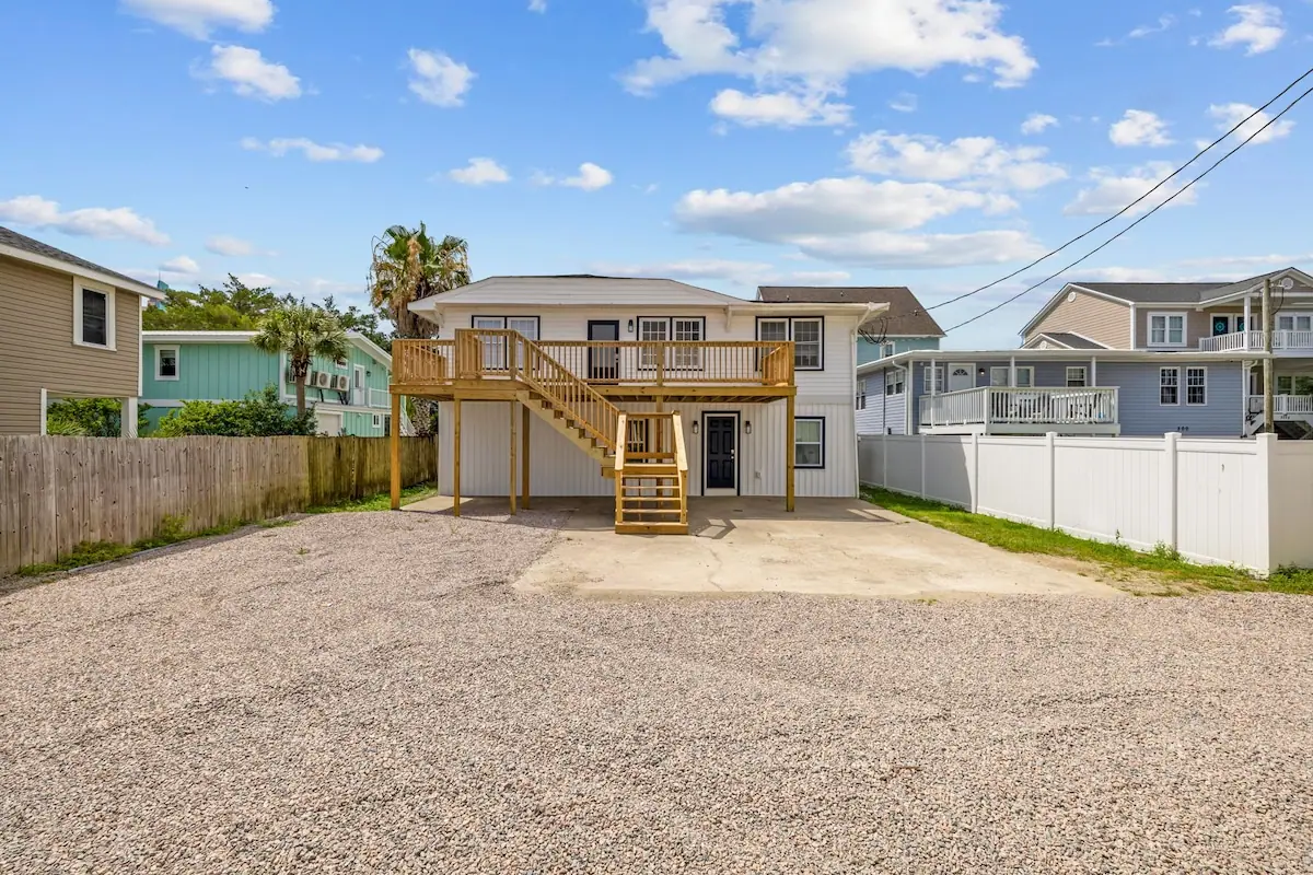 Two-story duplex with exterior stairs and a gravel parking area