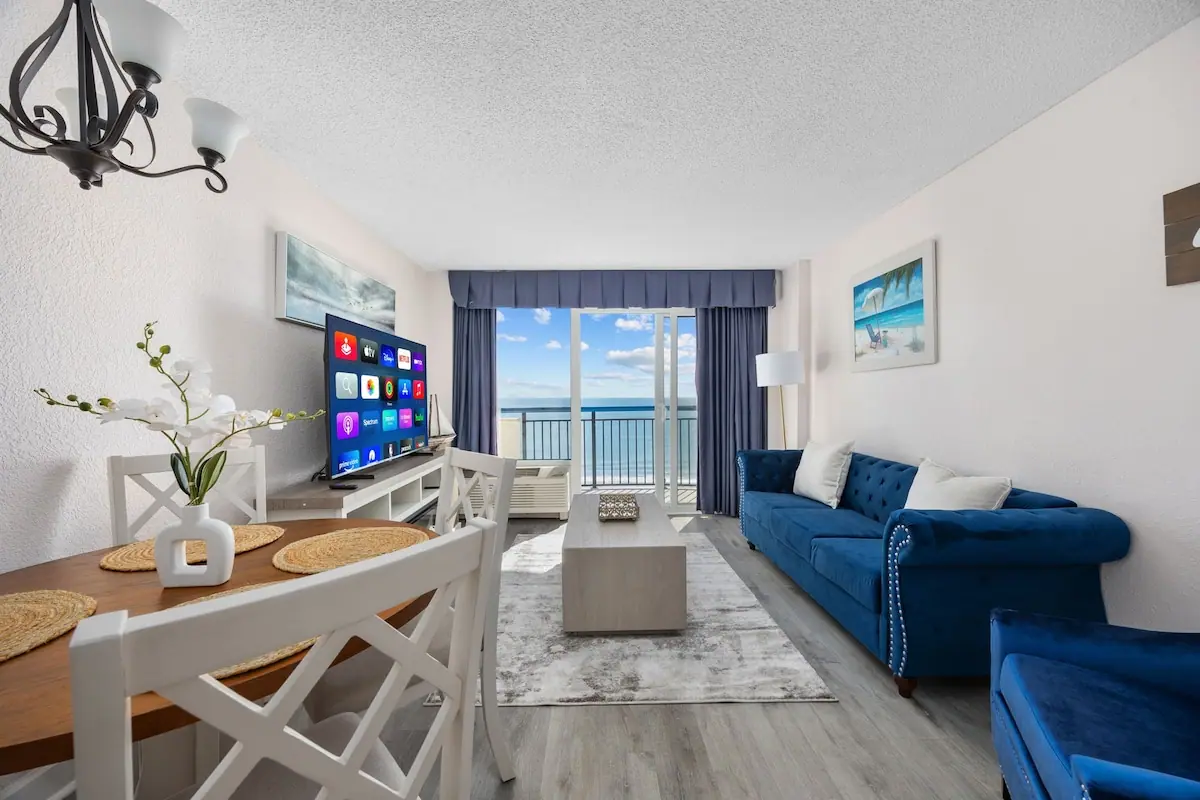 Living room with blue sofas and the ocean visible beyond the balcony