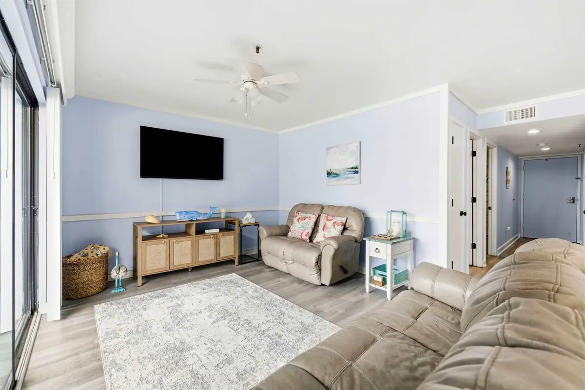Living room with gray sofas, a wall-mounted television, and pale blue walls